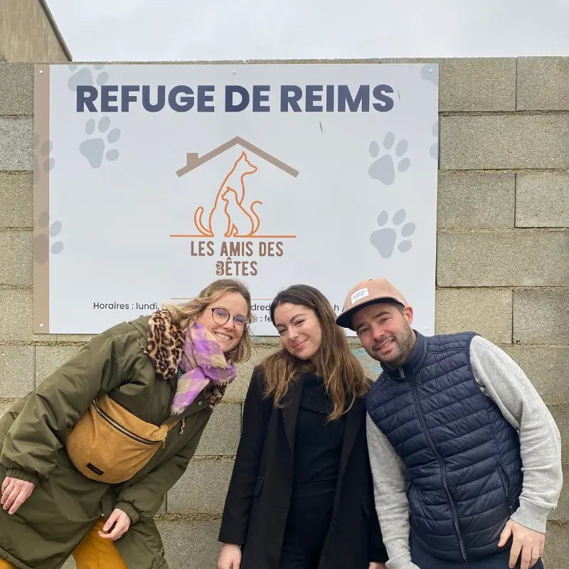Trois membres de l'équipe de la marque pour chat Jopy devant l'entrée d'un refuge soutenu par la marque